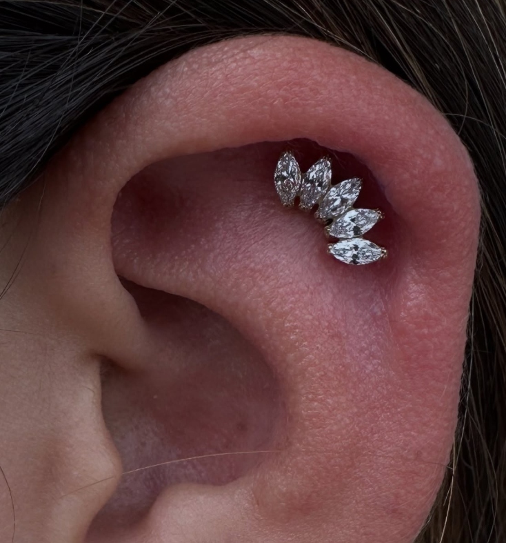 Professional helix ear piercing with a curved gem cluster by a Final Touch Tattoo piercer in San Antonio