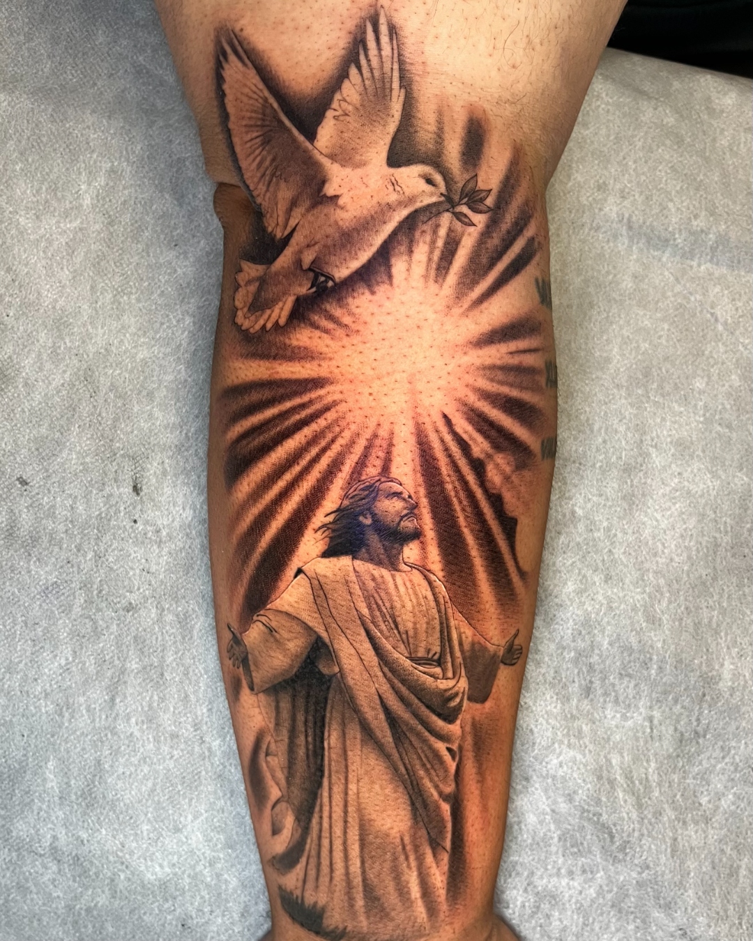 Black and gray religious realism tattoo with a glowing sunburst framed to the leg
