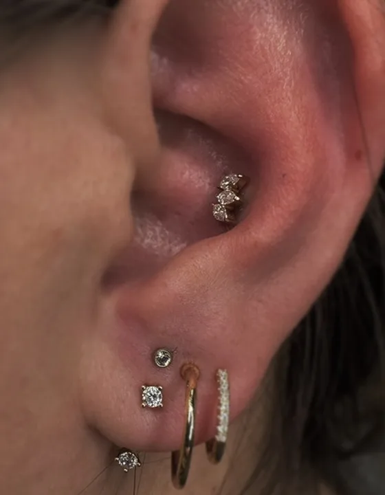 Ear piercings with gold and diamond jewelry by Kara
